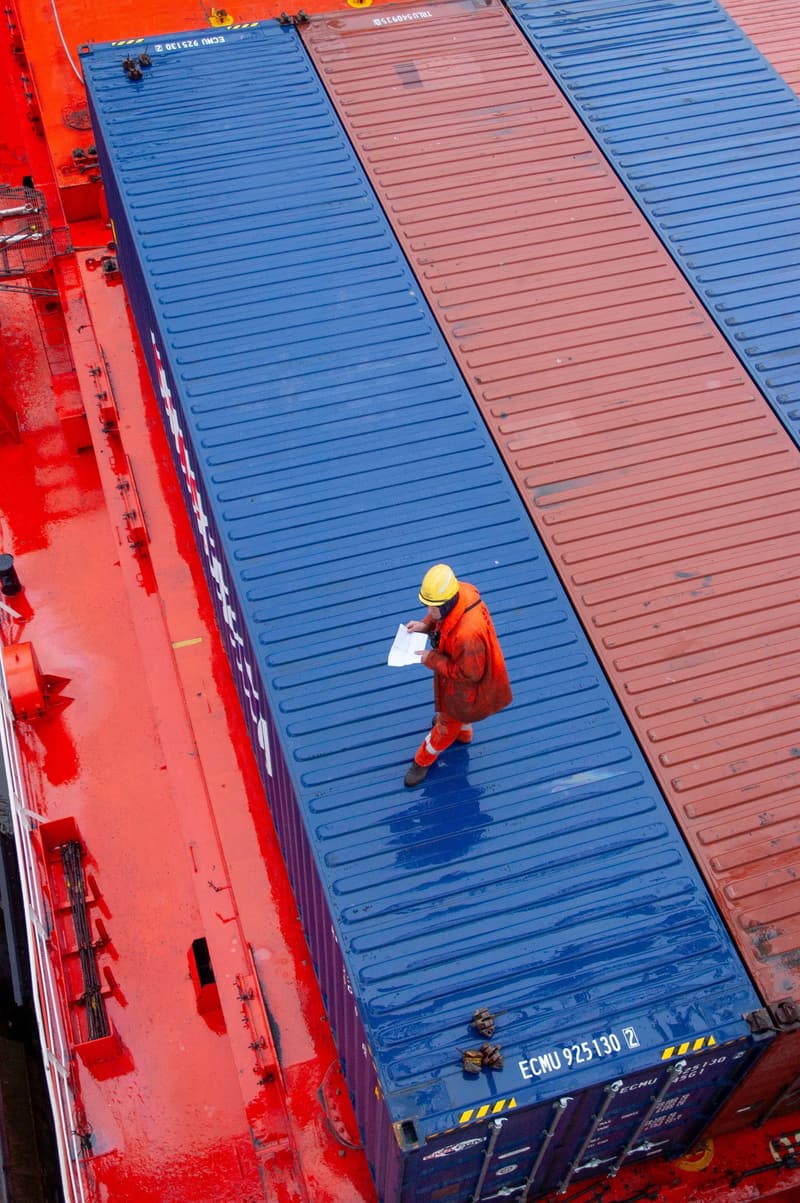Worker checking containers stacked aboard a container ship