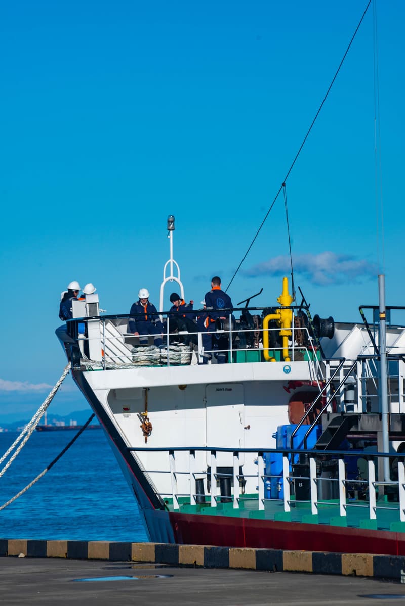 Crew working together on the deck of a vessel alongside the quay